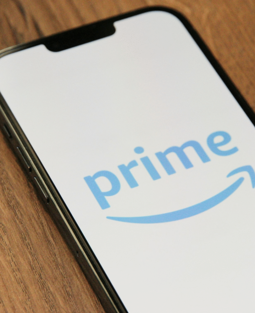 Amazon Prime vale a pena: logotipo do serviço exibido na tela de um celular sobre uma mesa de madeira.