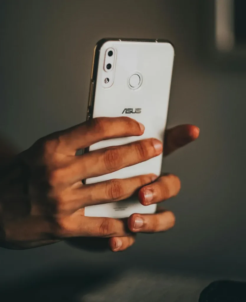 Pessoa segurando um smartphone Asus branco – imagem representando uso cotidiano de celulares baratos e originais em 2025.